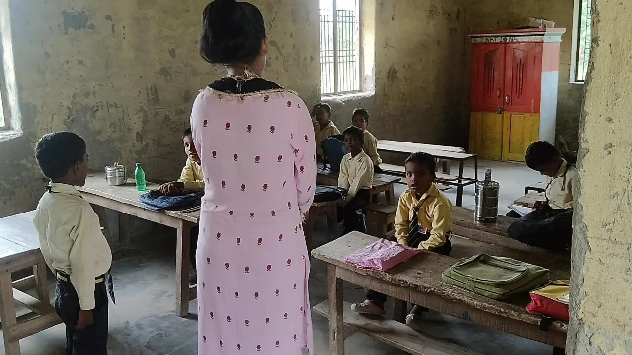 स्कूल में बच्चों को पढ़ती शिक्षिका